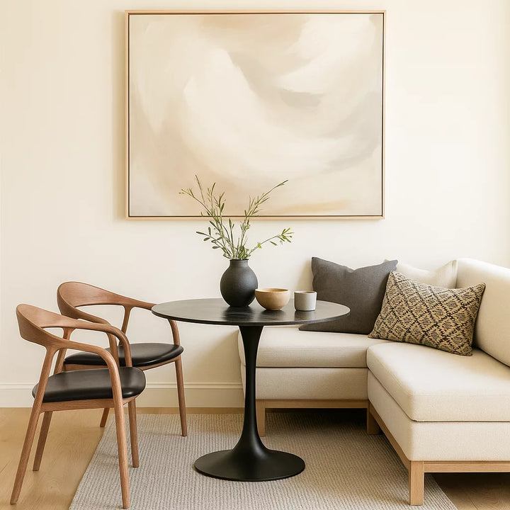 A cozy living room featuring a couch, a table, and a painting, with a Solid Wood Beech Dining Chair with Black Leather Cushion.