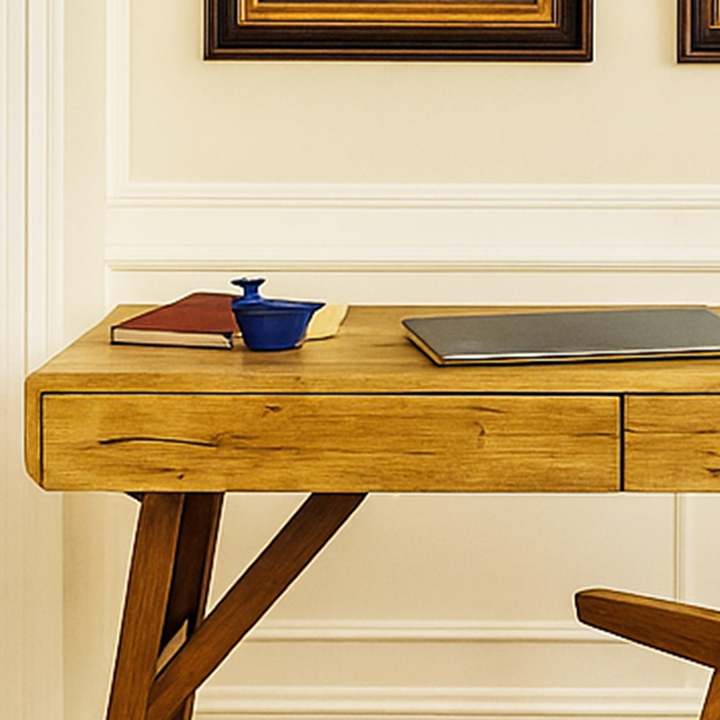 Wooden desk with a laptop, notebook, and blue container against a beige wall.