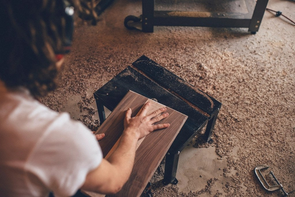 Walnut board being sanded by hand in a woodworking shop