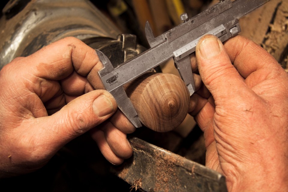 Woodworker measuring a solid wood piece with calipers
