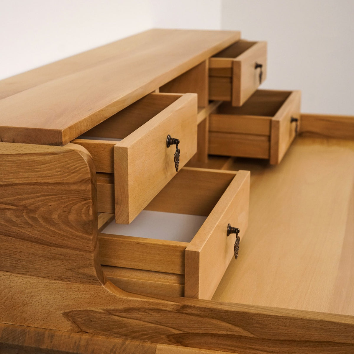 Close-up from above of three open hutch drawers with antique-style pulls on the beech writing desk