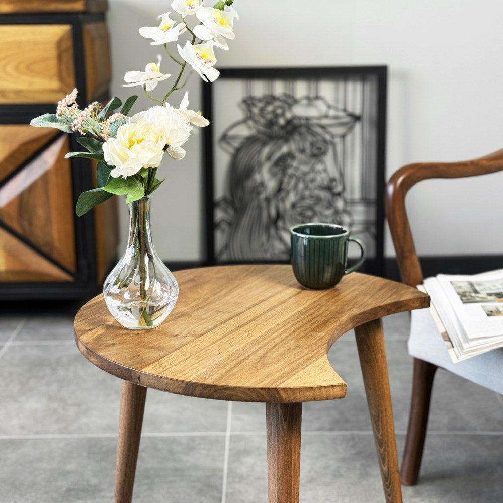 Walnut C-shaped end table top and tapered legs at a close angle, with a glass vase of flowers