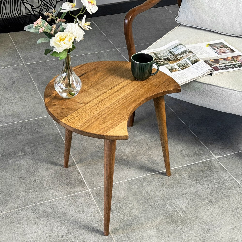Walnut C-shaped side table with three tapered legs seen from above, a glass vase on top