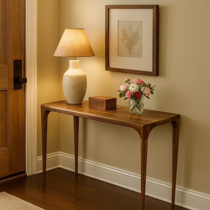 A walnut console table featuring a decorative lamp and a bouquet of flowers, enhancing the room's aesthetic appeal.
