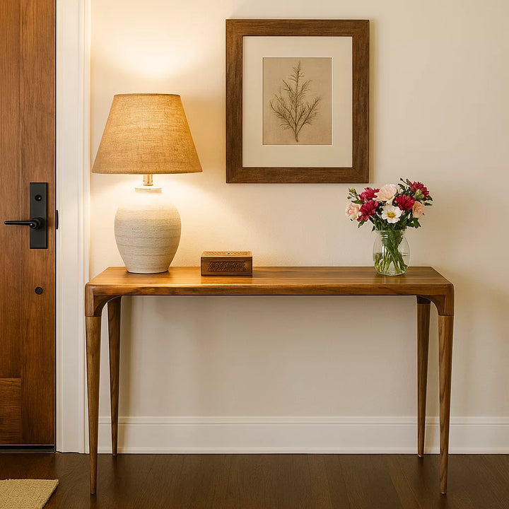 A walnut console table featuring a stylish lamp and a bouquet of flowers, enhancing the room's decor.