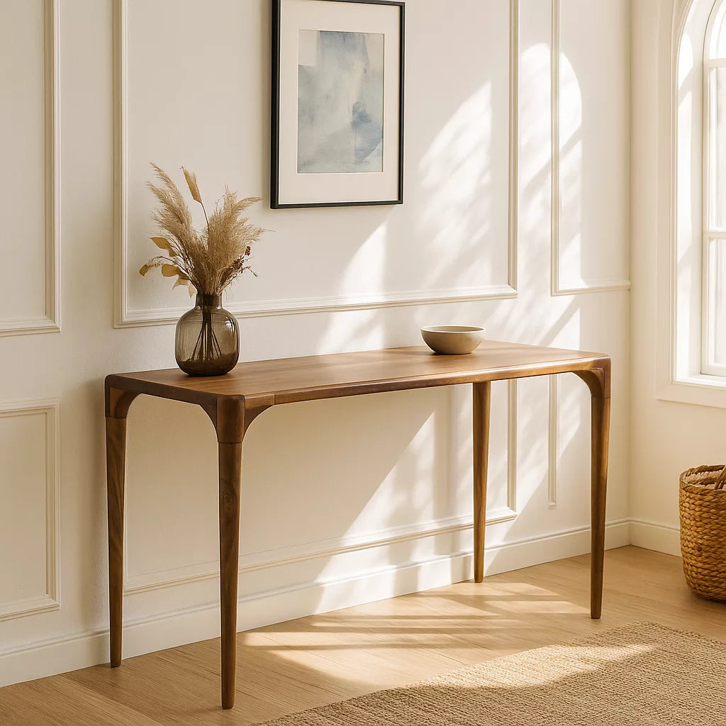 A walnut console table set against white walls in a room with a window, offering a stylish and airy environment.
