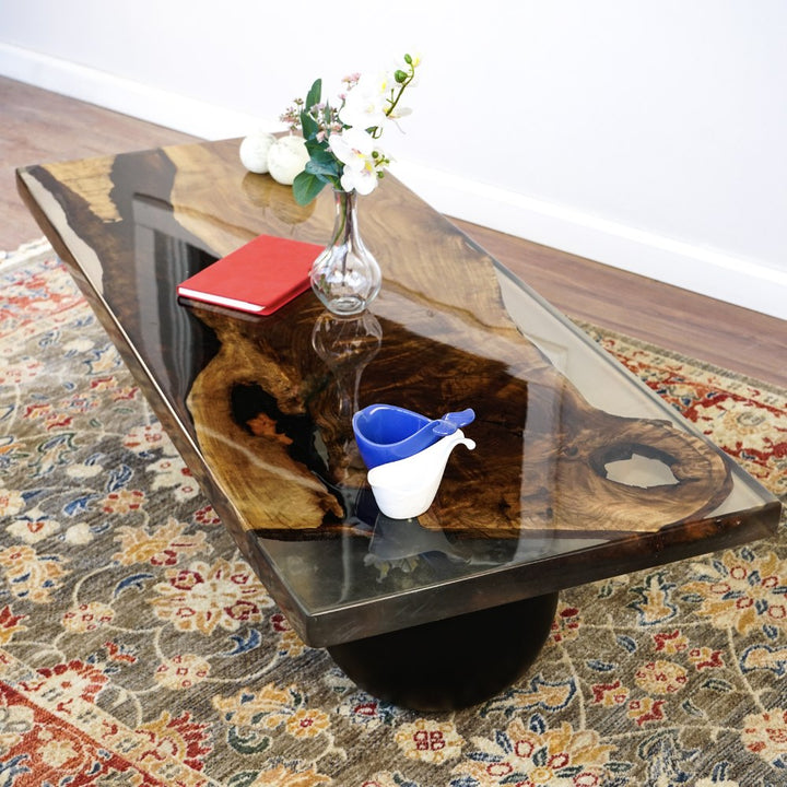 High angle view of the walnut slab and clear epoxy top on the coffee table with a black ball leg