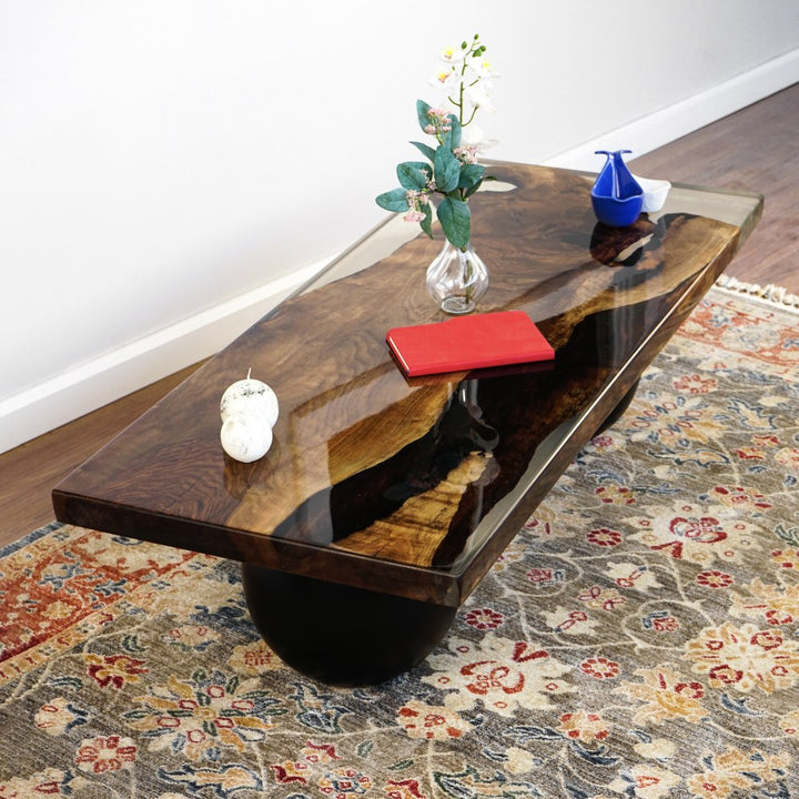 Walnut epoxy coffee table top seen at a raised angle, showing the dark river and live edge