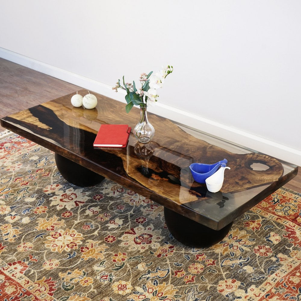 Walnut live edge epoxy coffee table on black ball legs, angled view from the end on a rug