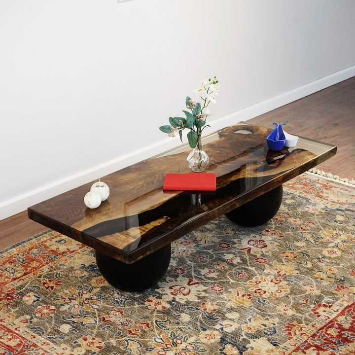 Walnut live edge epoxy coffee table on two black wooden ball legs, angled view from the end on a patterned rug