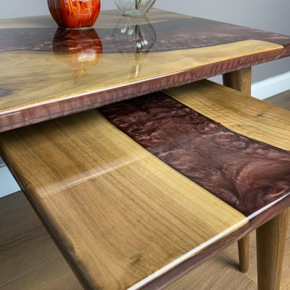 Close-up of the small walnut nesting table top with burgundy epoxy beneath the large table edge