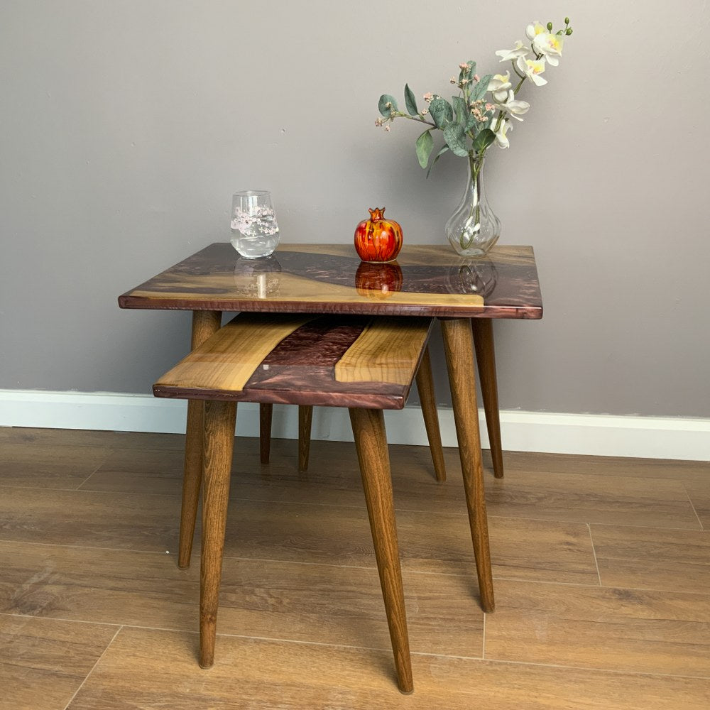 Front view of the large walnut nesting table with the small burgundy epoxy table nested beneath
