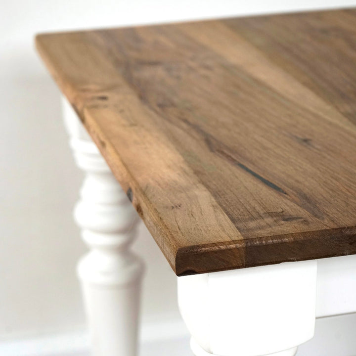 Close-up of the walnut top edge and white turned leg of the side table