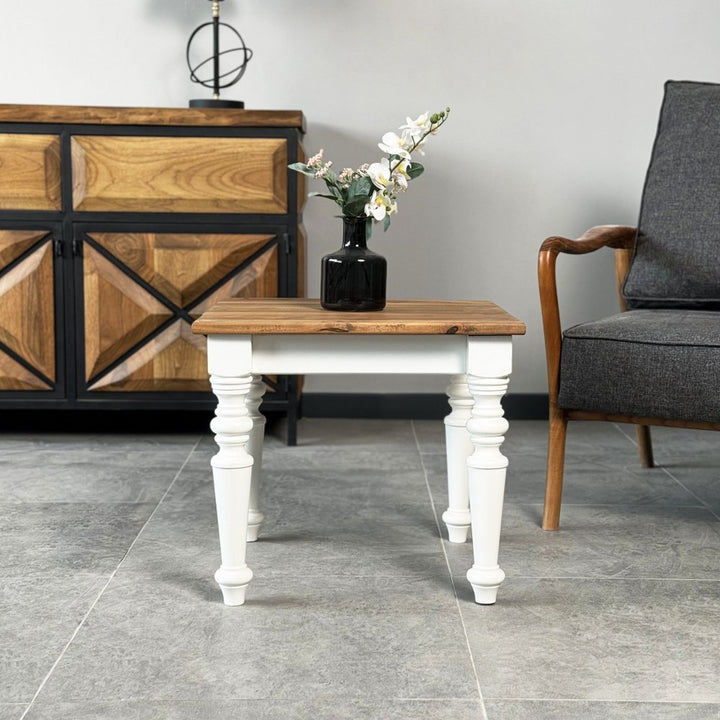 Wide view of the side table with walnut top and white legs in front of a sideboard