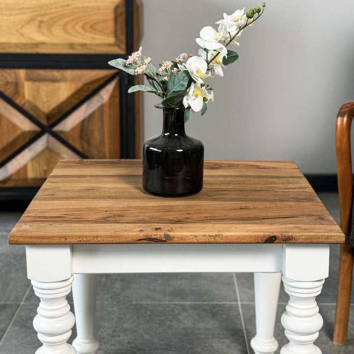 Front close-up of the walnut top and white turned legs of the side table