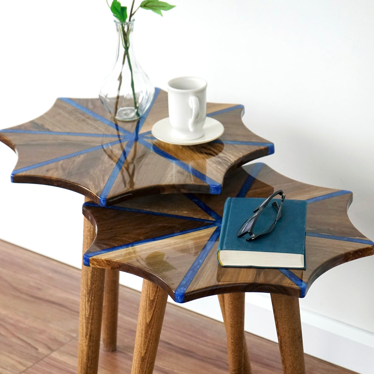 Close-up of the stacked snowflake walnut side tables with blue epoxy stripes and a book on top