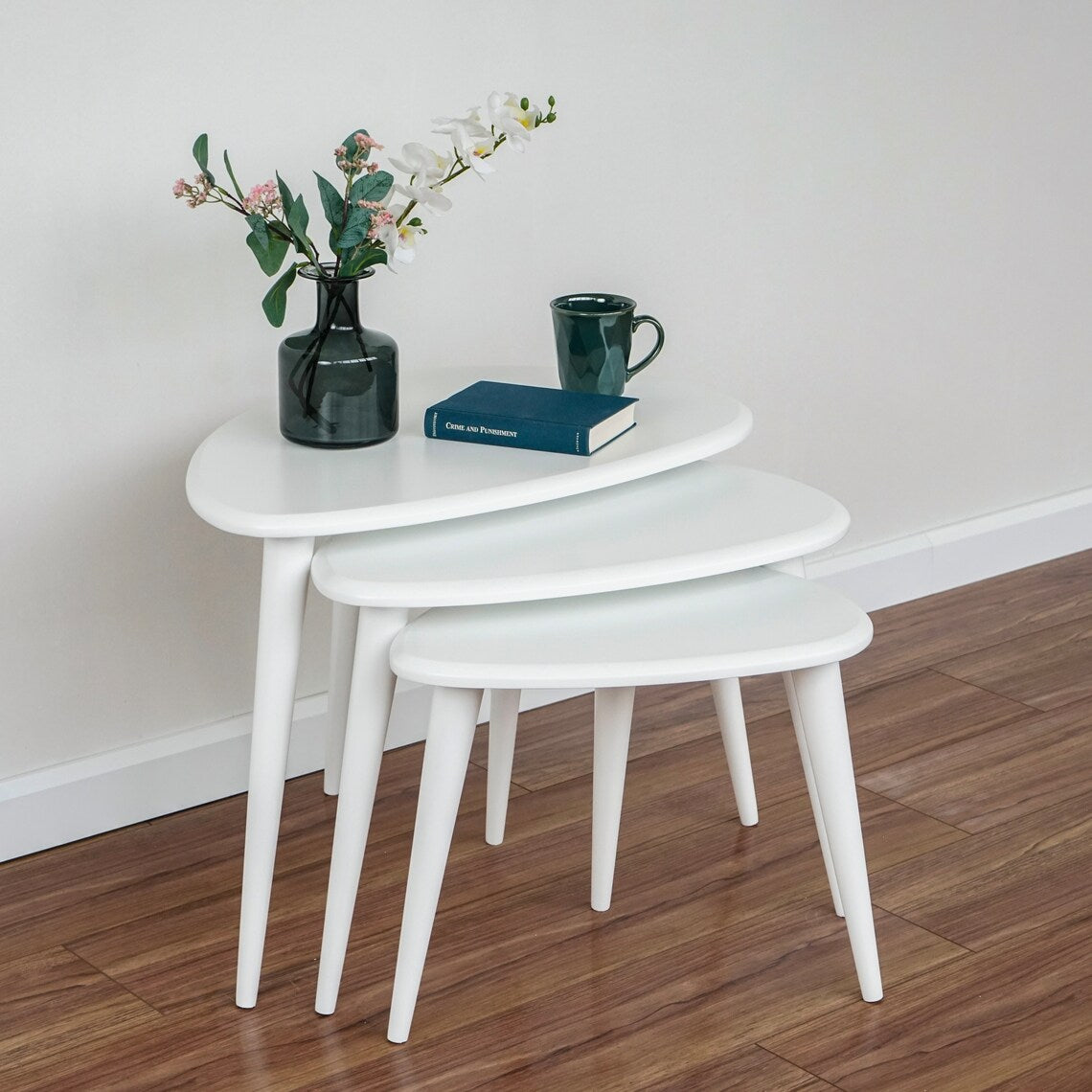 White nesting coffee table set of 3 with a vase on the largest table, side view
