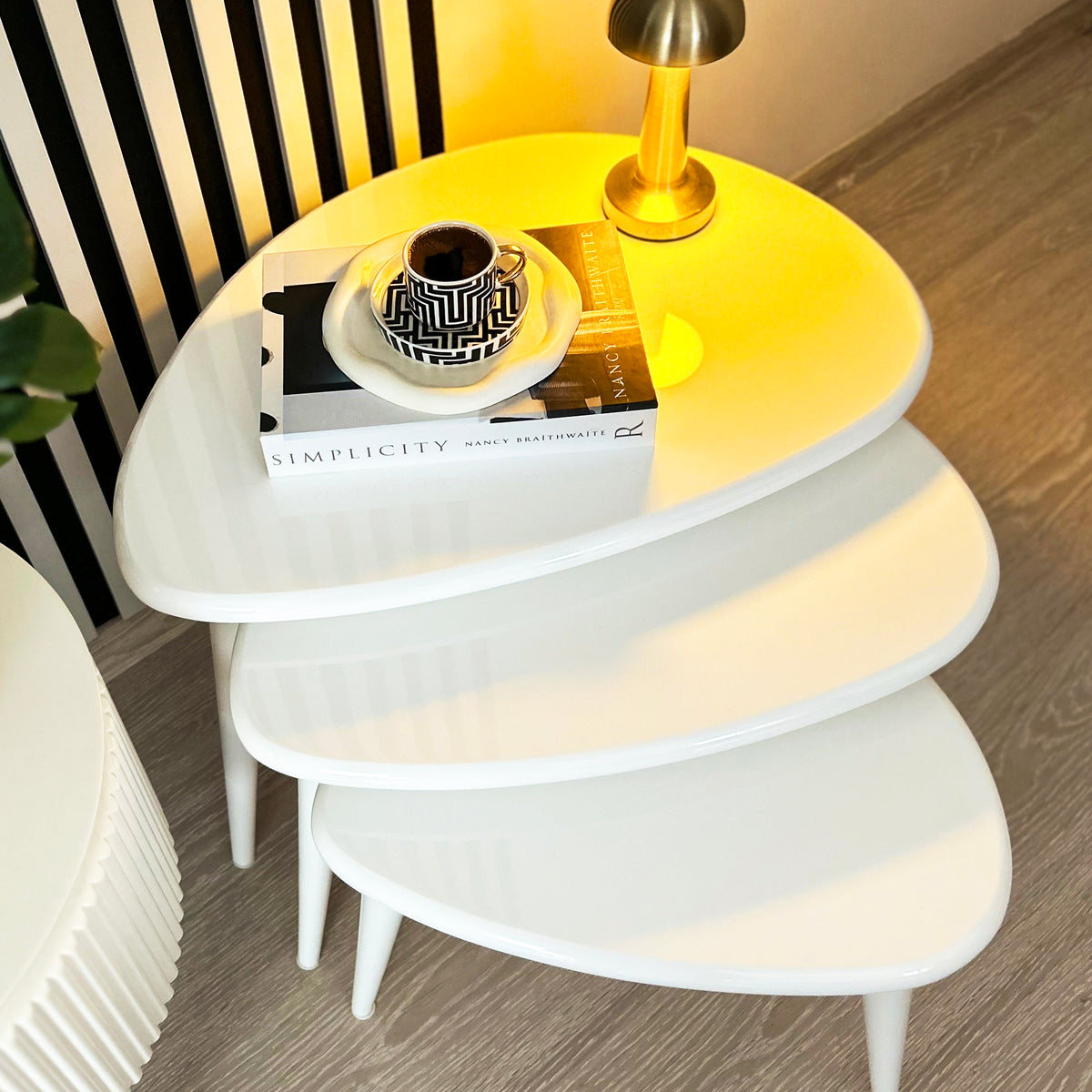 Top view of the white high gloss lacquer nesting tables with the lamp glow reflected on the surface