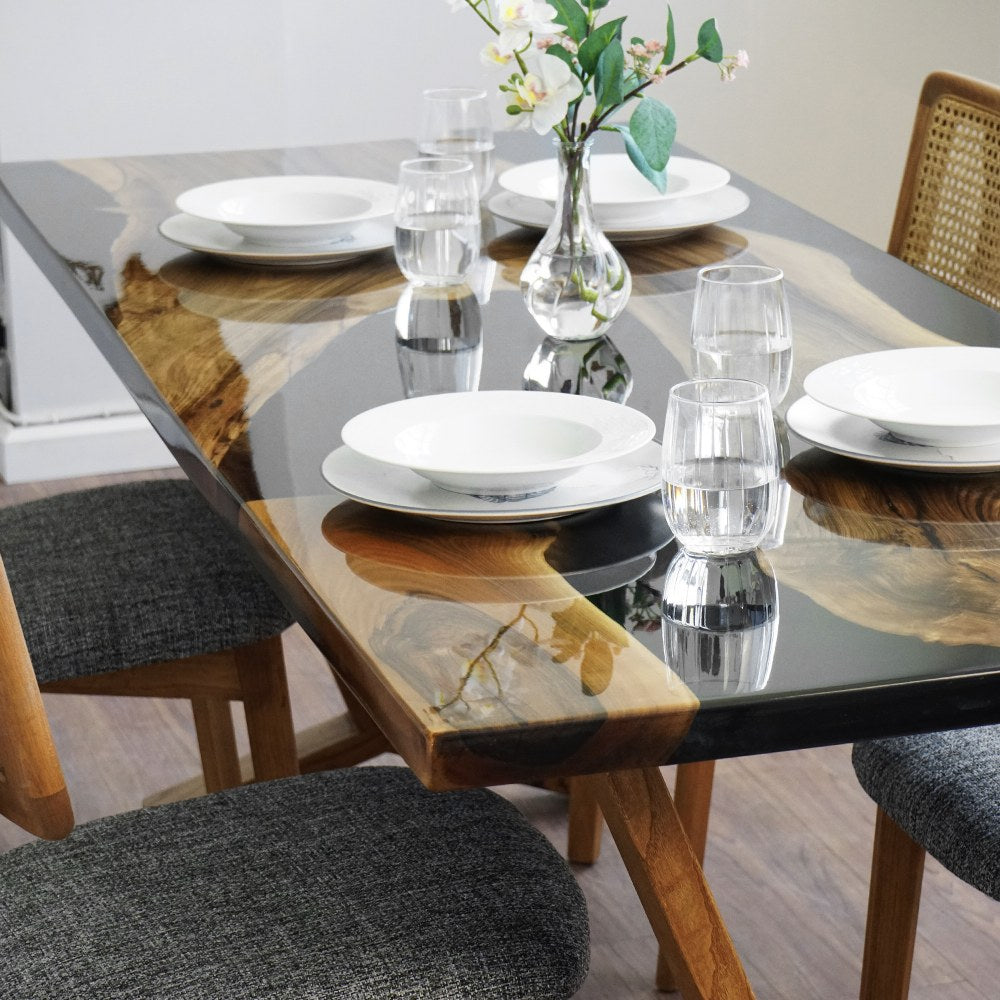 Close-up of the black epoxy river and live edge walnut with place settings on the dining table