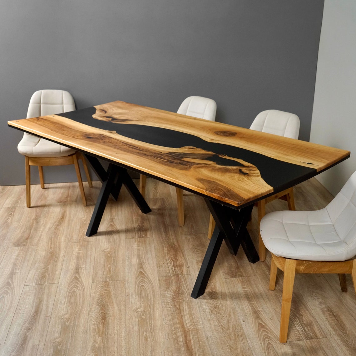 Black epoxy river walnut dining table with live edge planks and black X legs, angled view with white chairs
