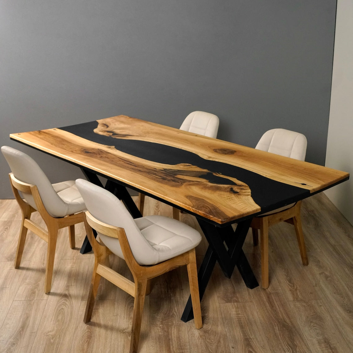 Black epoxy river dining table seen from a high end angle with white chairs and black X legs