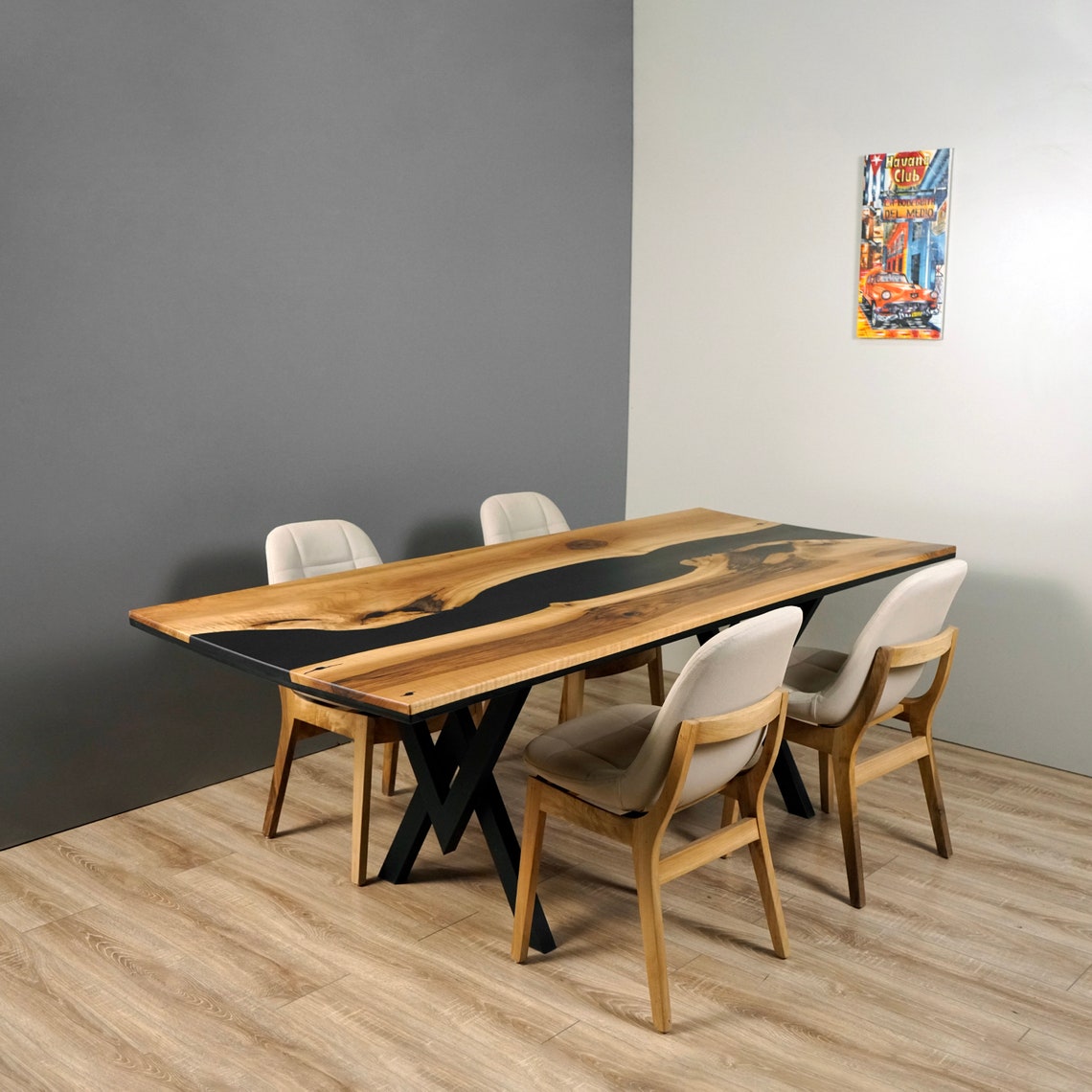Black epoxy river dining table from a low corner angle with four chairs in front of a gray wall