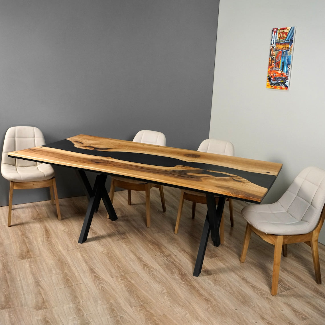 Black epoxy river dining table with X legs, side view with white chairs and a colorful print on the wall