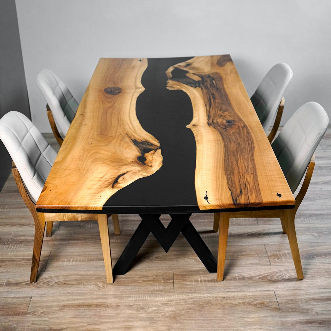 Straight-on top view of the black epoxy river dining table with four white chairs around it
