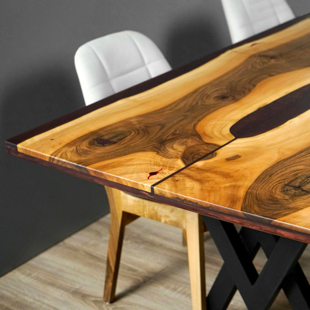 Close-up of the live edge corner and burgundy epoxy river on the walnut dining table, with a chair beside it