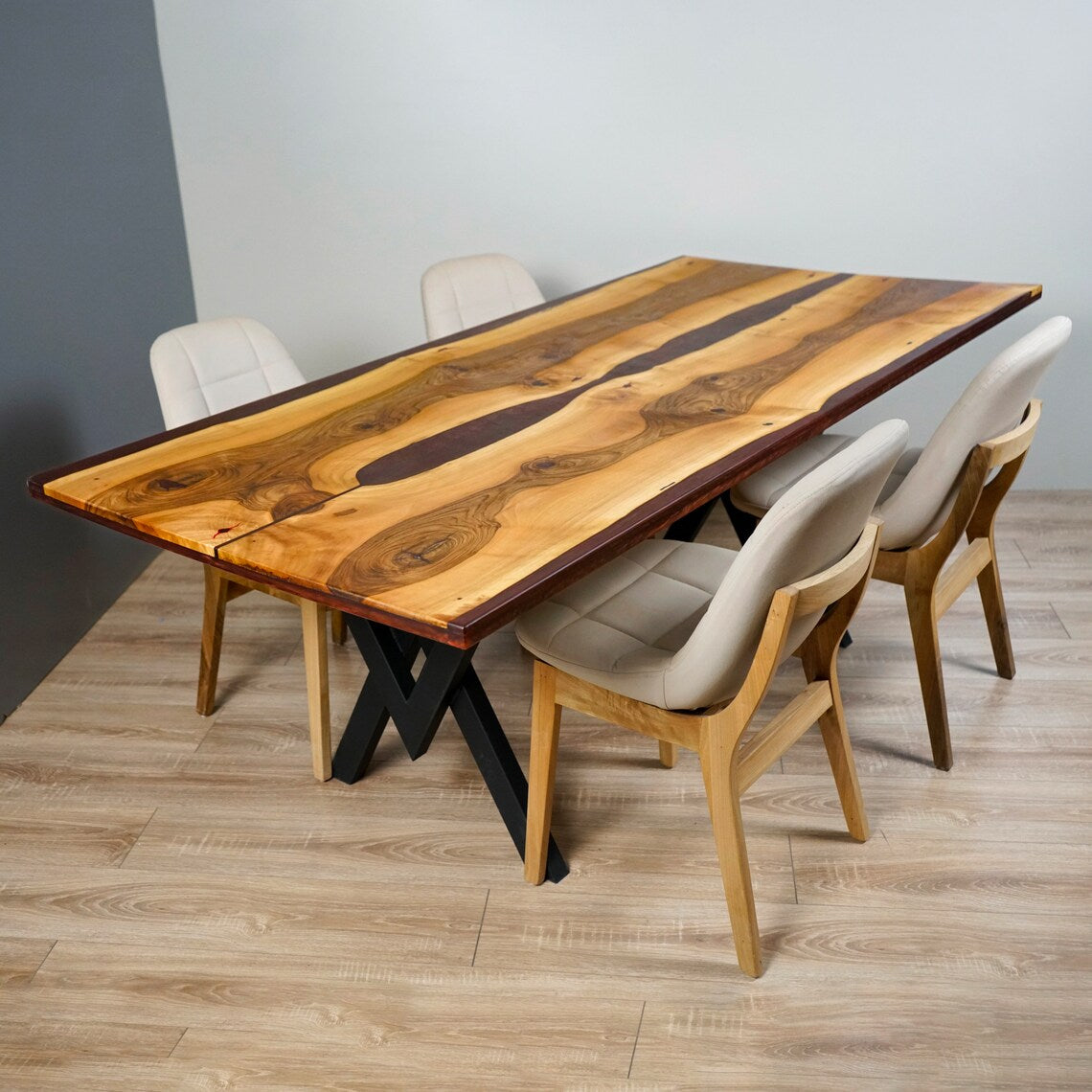 Walnut dining table with burgundy epoxy and metal legs, side angle with chairs pulled up to the long edge