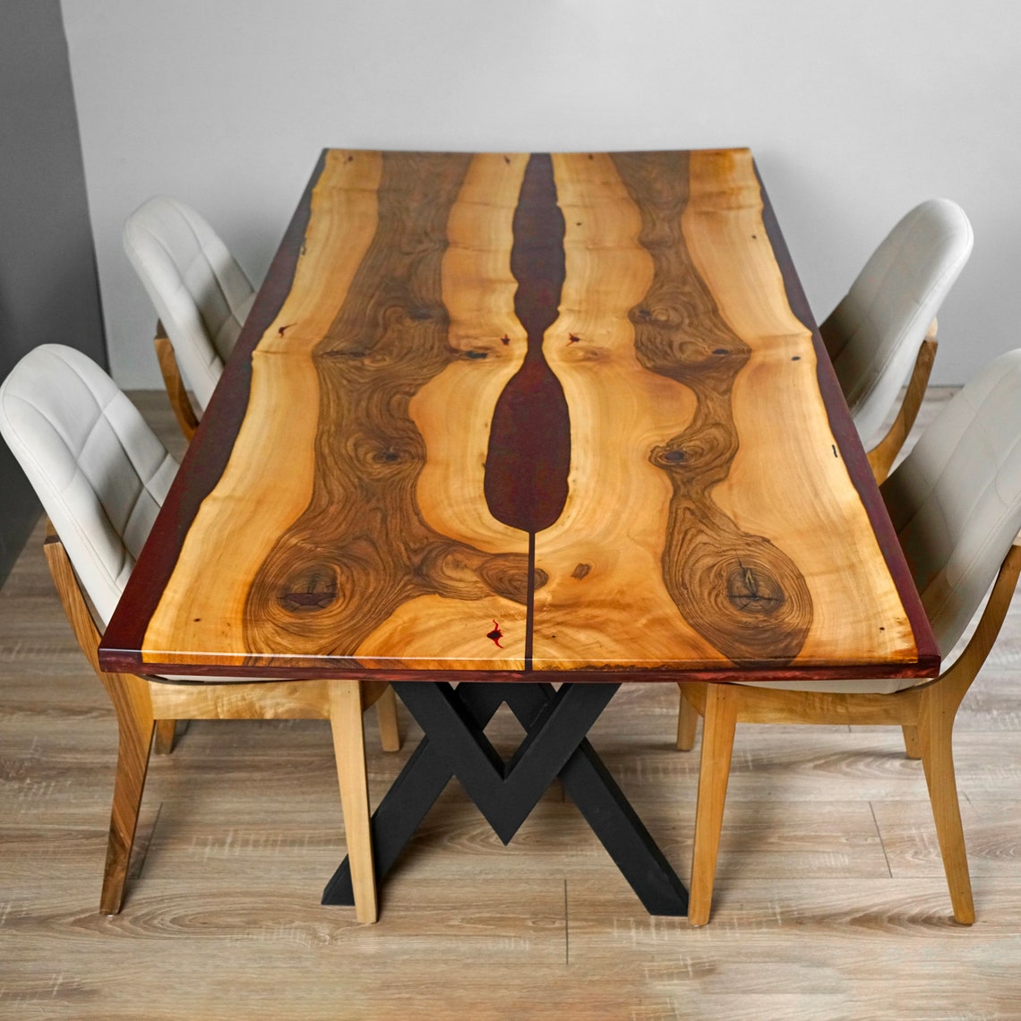 Top view of the walnut dining table showing the burgundy epoxy river between two live edge slabs