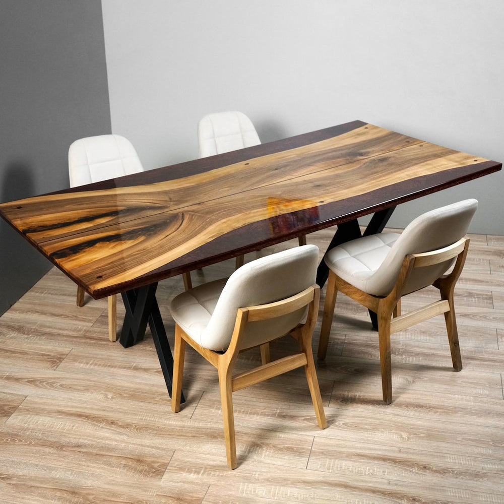 Corner view of the walnut live edge dining table with burgundy resin edges and black X legs