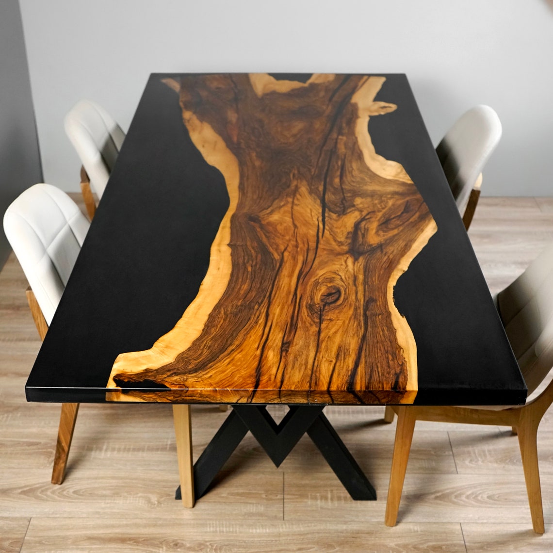 Top view of the walnut live edge strip set in a black epoxy dining table with cream chairs