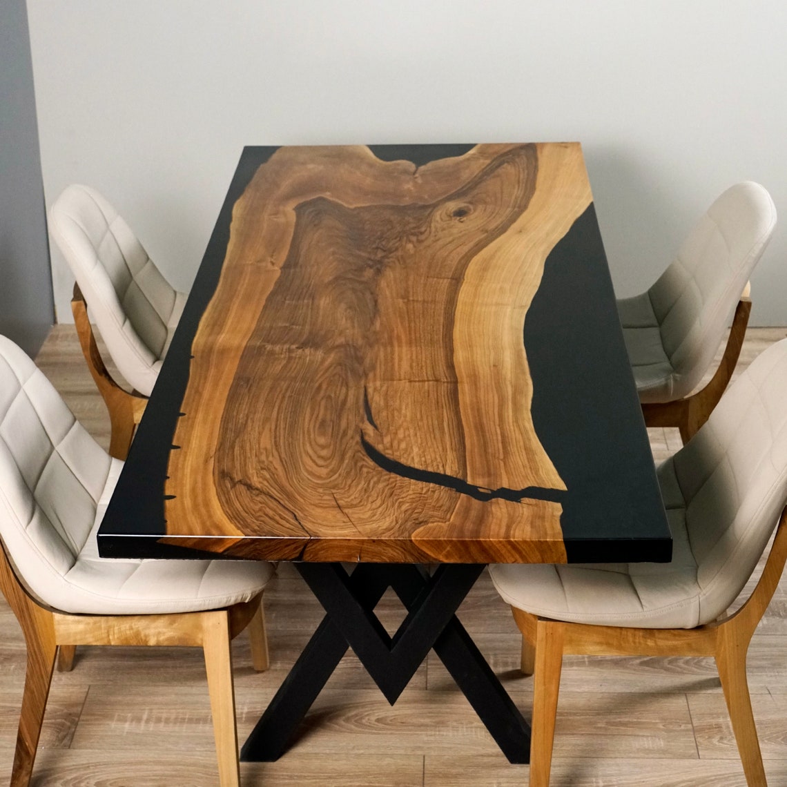 Top view of the live edge walnut dining table, black epoxy channel beside the walnut grain, chairs at both sides