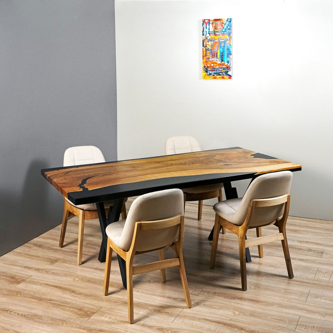 Live edge walnut dining table with black epoxy seen from the side, two chairs pulled up at the front