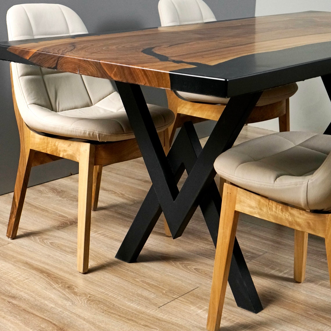 Close-up of the black epoxy edge and crossed black metal legs of the live edge walnut dining table