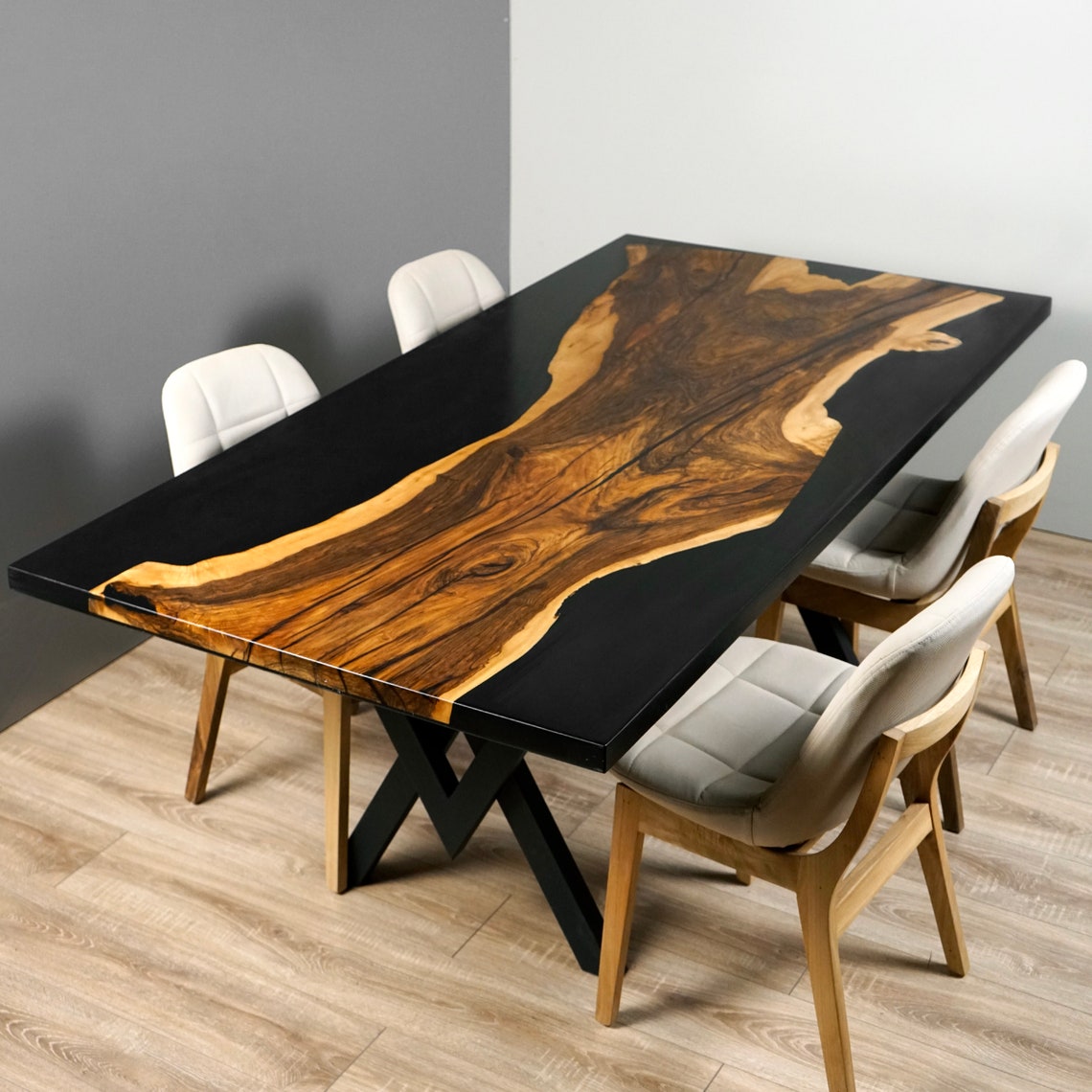Live edge walnut dining table with black epoxy top and X shaped base from a corner angle
