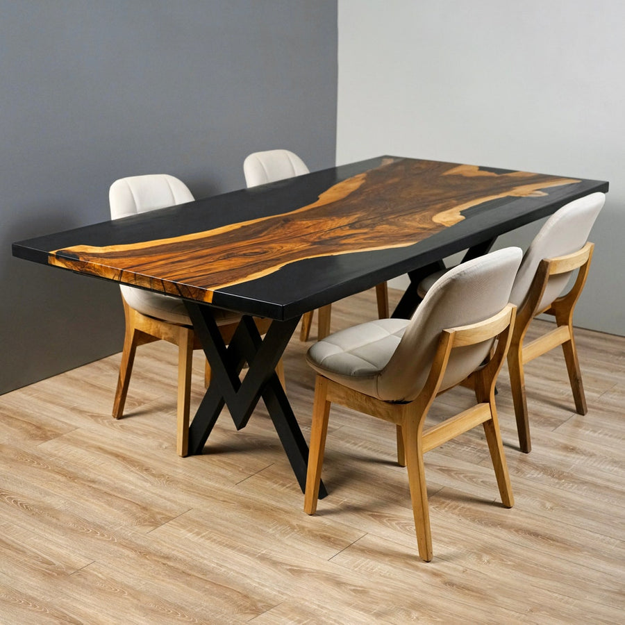 Midnight walnut live edge dining table with a black epoxy top and X shaped base beside four cream chairs