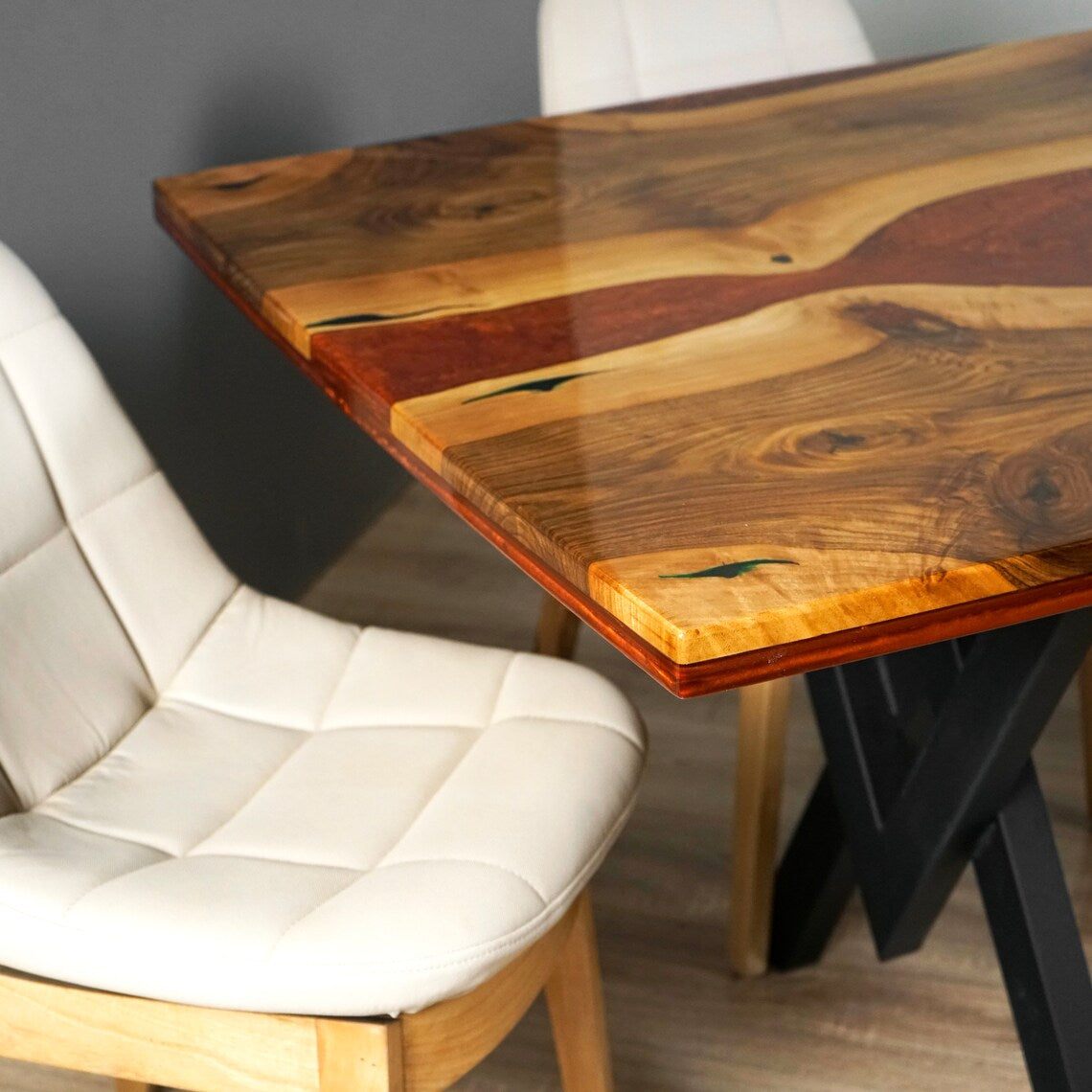 Close-up of the burgundy epoxy river and live edge corner of the walnut dining table, with a chair beside it