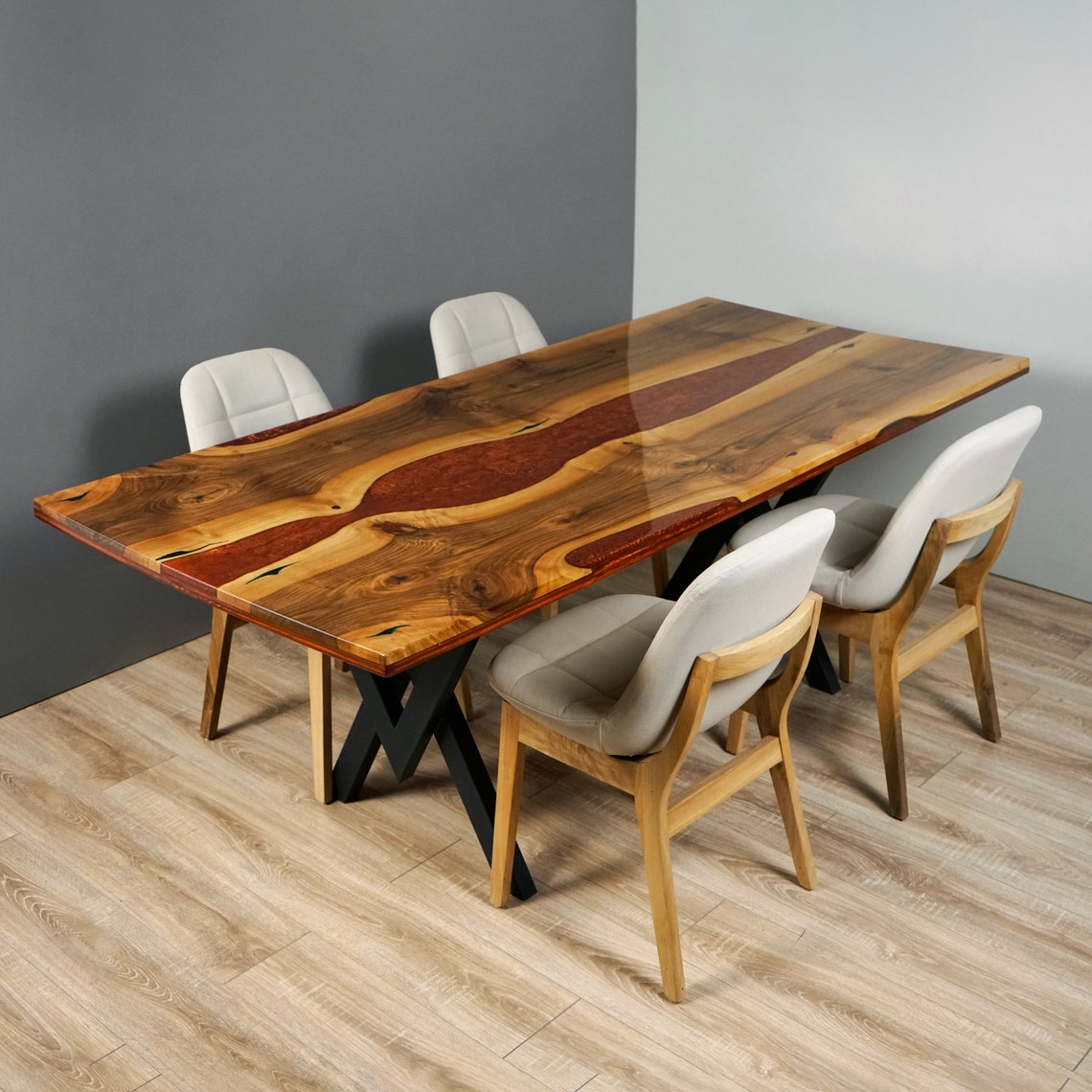 Amber live edge walnut dining table with a burgundy epoxy river and black metal legs, with four chairs