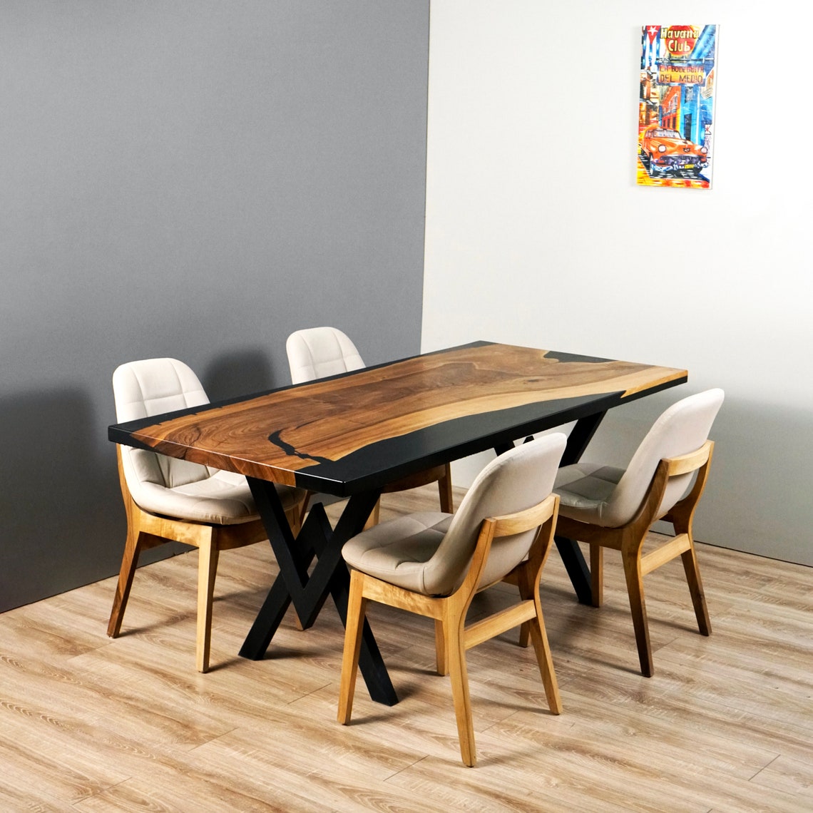 Walnut dining table with black epoxy and metal legs, front-corner view with four upholstered chairs against a gray wall