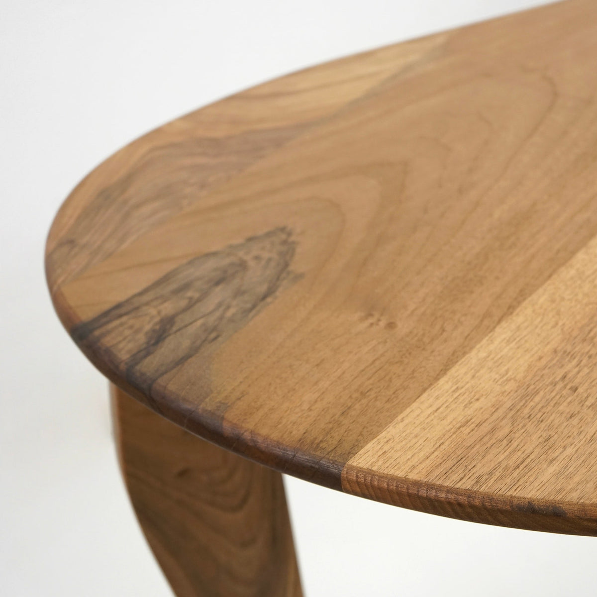 Close-up of the walnut desk's curved edge and natural grain on the top