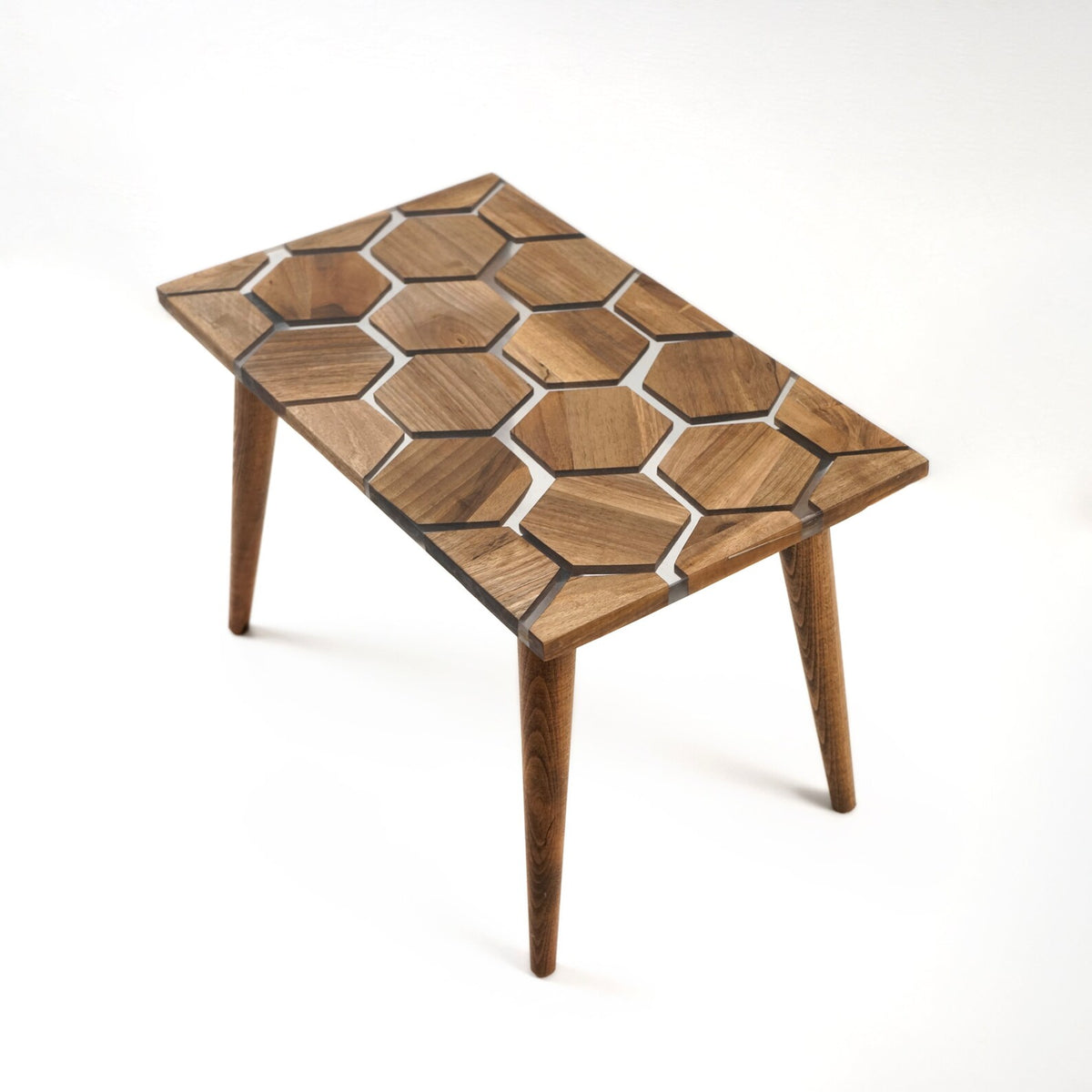 Walnut epoxy coffee table with honeycomb top, angled from the short end on a white background