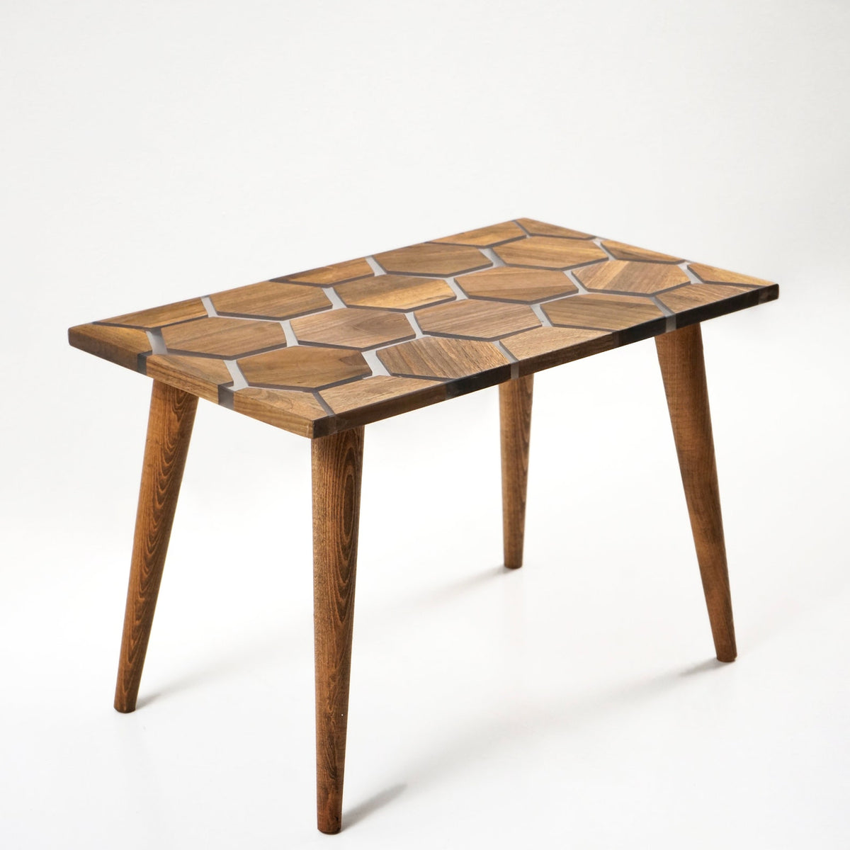 Walnut epoxy coffee table with honeycomb top, angled from the long side on a white background