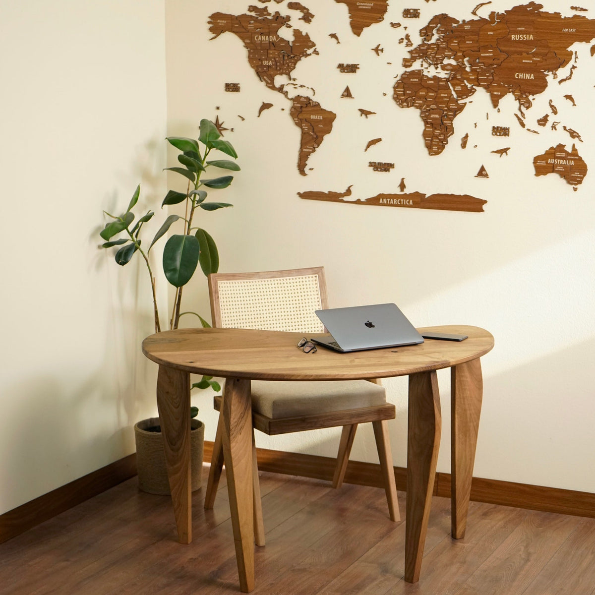 Wide view of the bean shaped walnut desk and rattan chair in a corner beside a floor plant