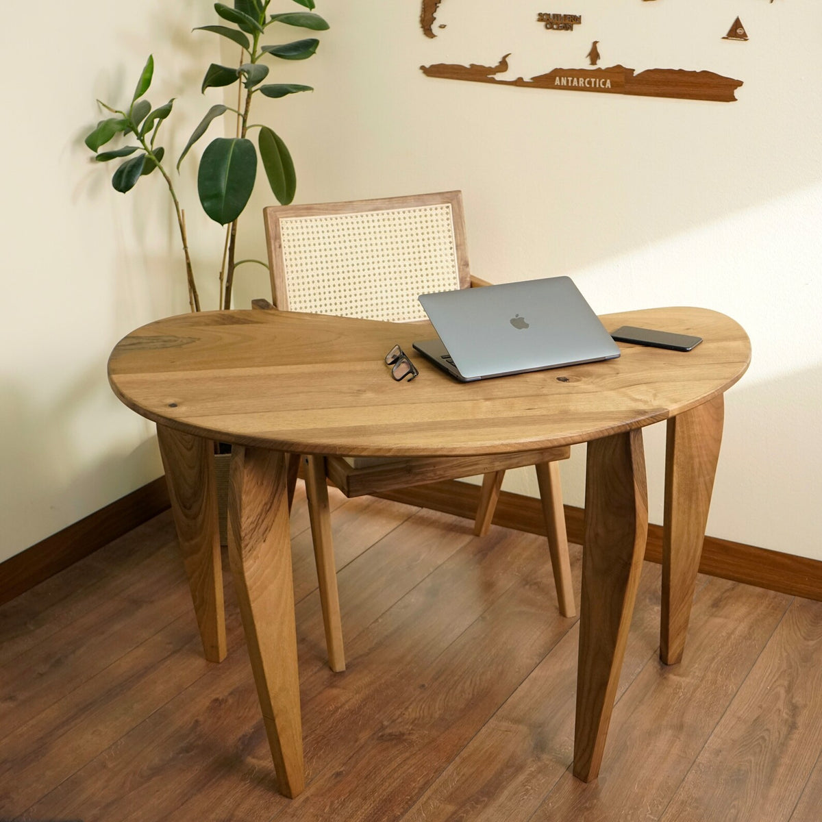 Bean shaped walnut desk with tapered legs and a rattan back chair in a corner home office