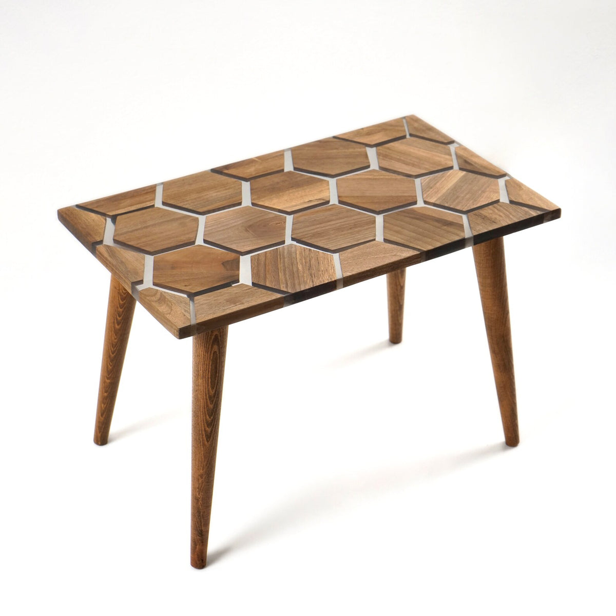 Walnut epoxy coffee table with honeycomb pattern top and tapered legs on a white background