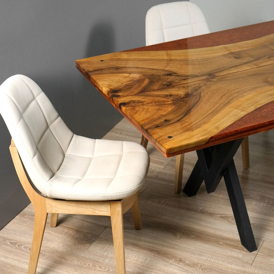 Burgundy epoxy live edge walnut kitchen table with black X-shaped legs, close corner view with cream chairs