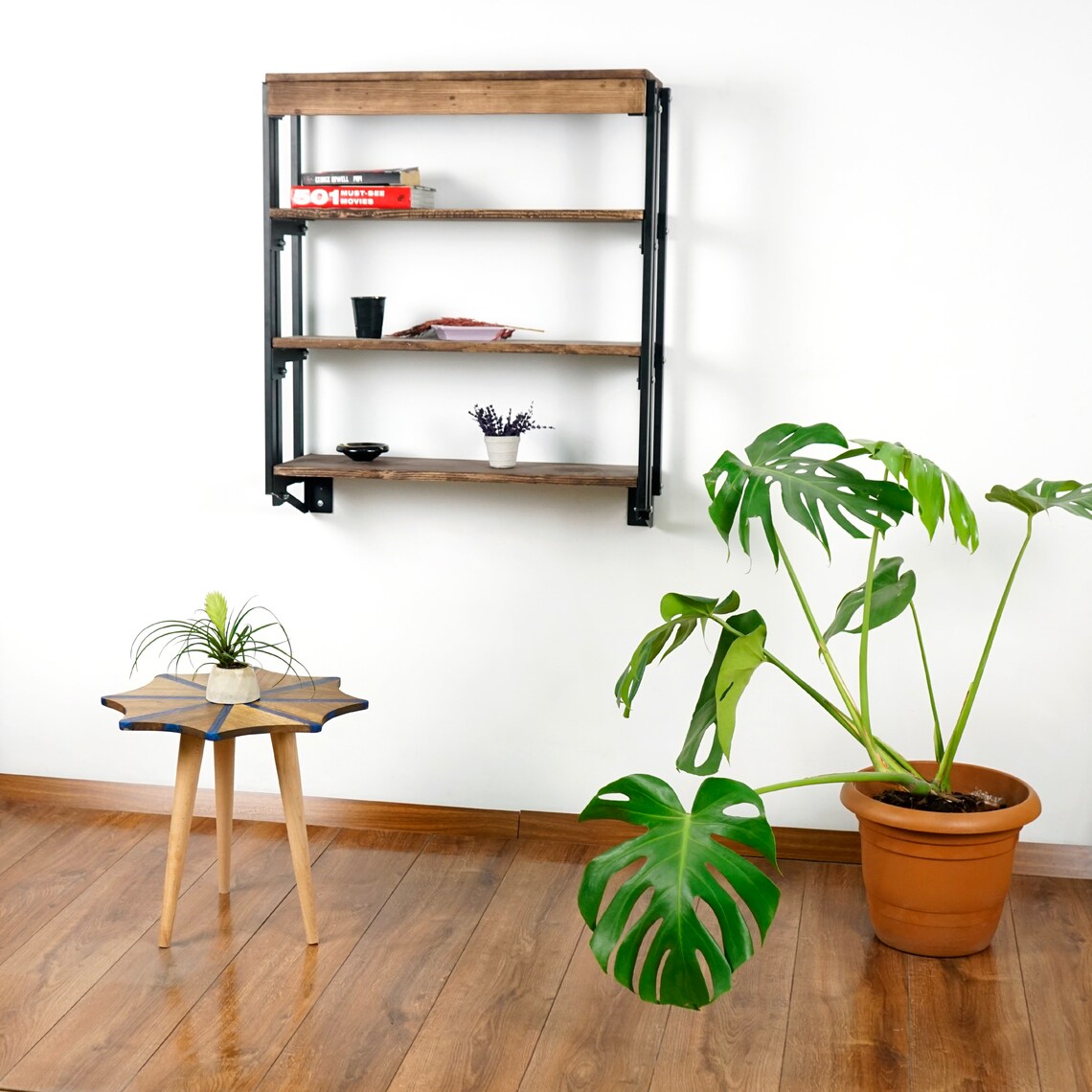 Wide view of the small walnut snowflake side table with blue epoxy beside a wall shelf and plant