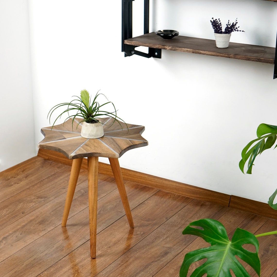 Walnut snowflake side table with white epoxy stripes and three tapered wooden legs in a room corner